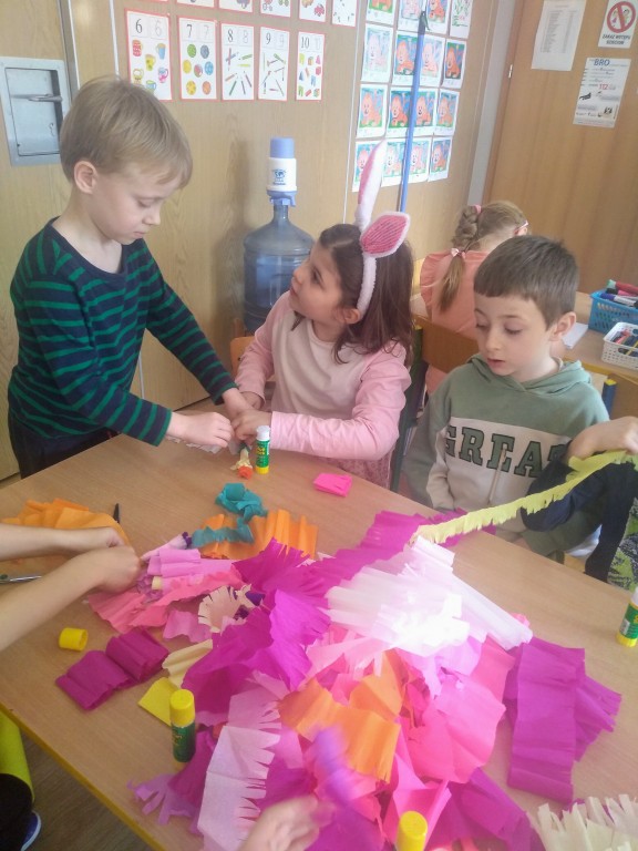 Michalina, Ignaś i Nikodem  przyozdabiają palmy kolorową bibułą